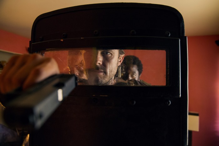 Casey Affleck and others behind a riot shield
