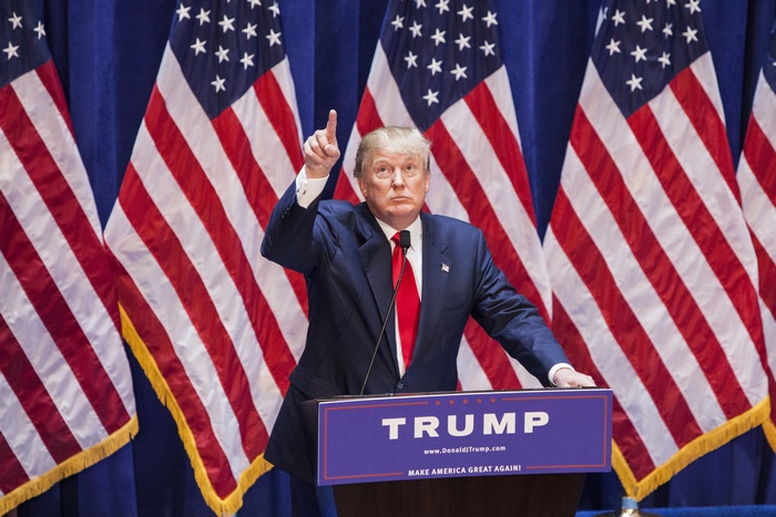 Donald Trump speaking at a podium with American flags