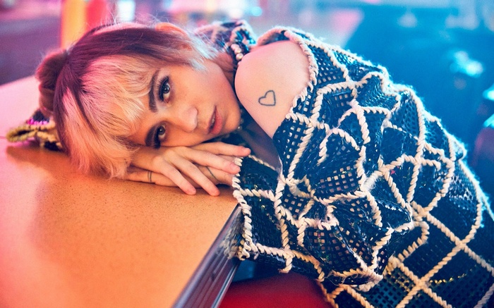 Woman with pink hair resting head on table