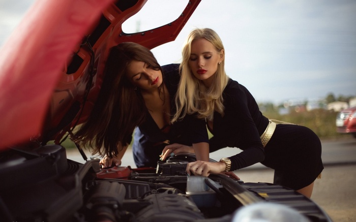 Two women looking at car engine