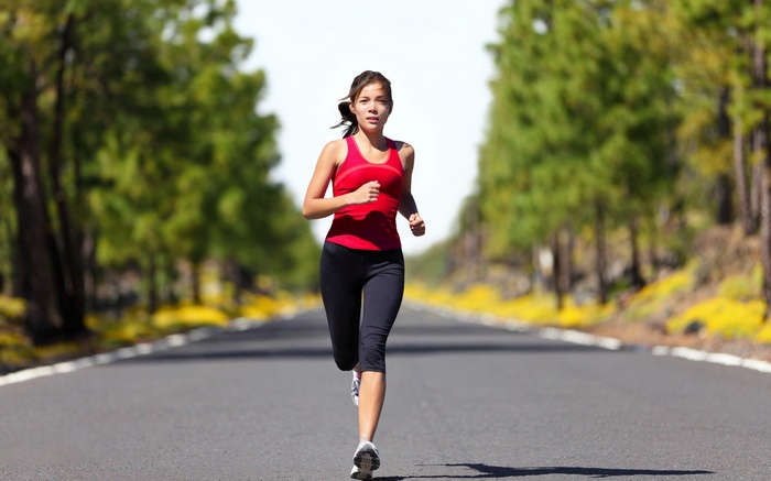 Woman running on a road lined with trees