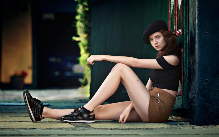 Woman in black beret and shorts sitting on ground