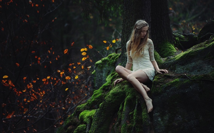 Woman sitting on mossy rocks in a forest