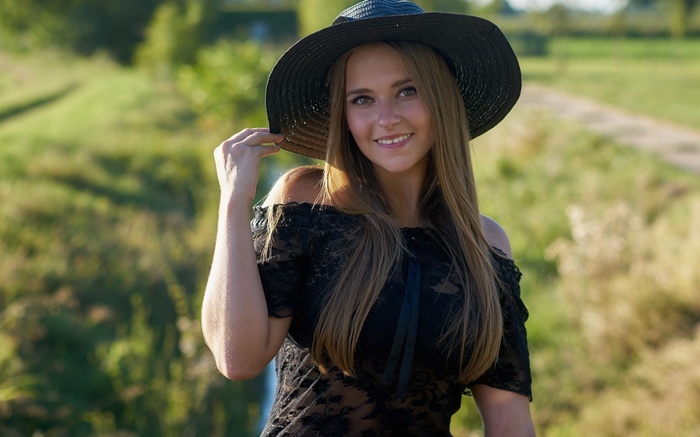 Woman in a black hat and dress outdoors