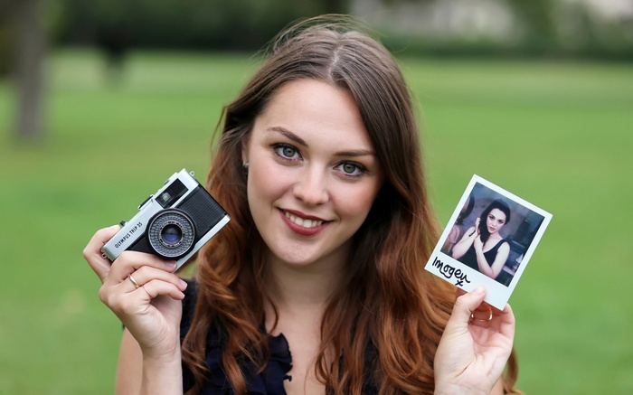 Woman holding an Olympus Trip 35 camera and a polaroid