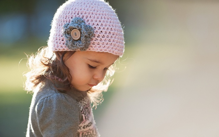 Young girl wearing a pink knitted hat and grey sweater