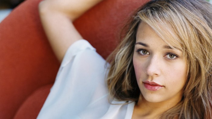 Rashida Jones lying on a red couch