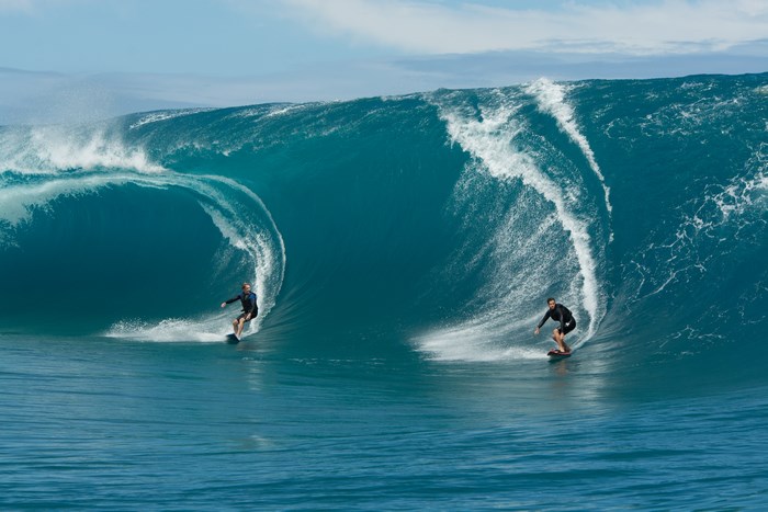 Two surfers riding giant waves
