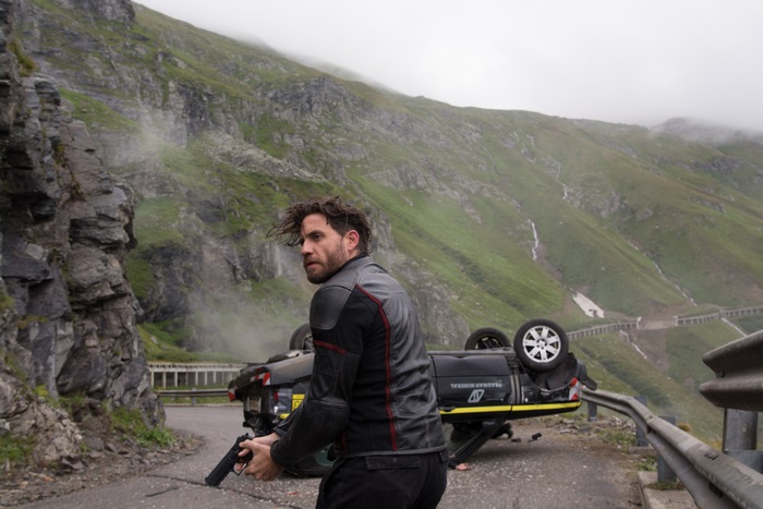 Edgar Ramirez with a gun on a mountain road