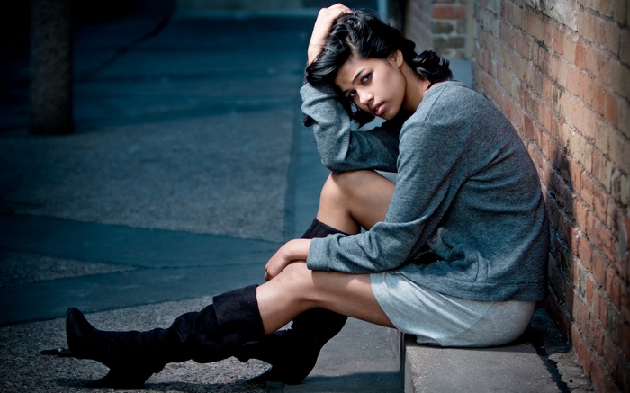 Woman sitting by a brick wall