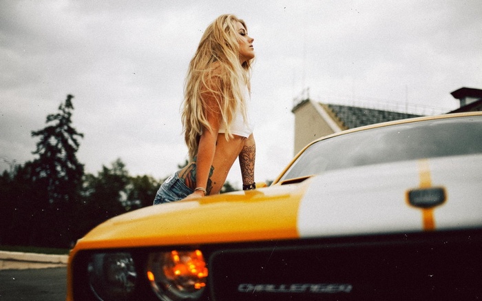 Woman leaning on a yellow Dodge Challenger