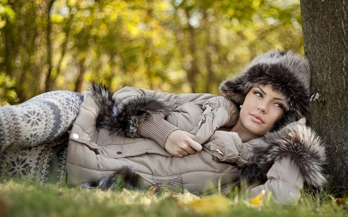 Woman in winter clothing lying in grass