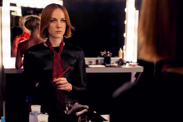 Jena Malone in a black outfit with a red tie