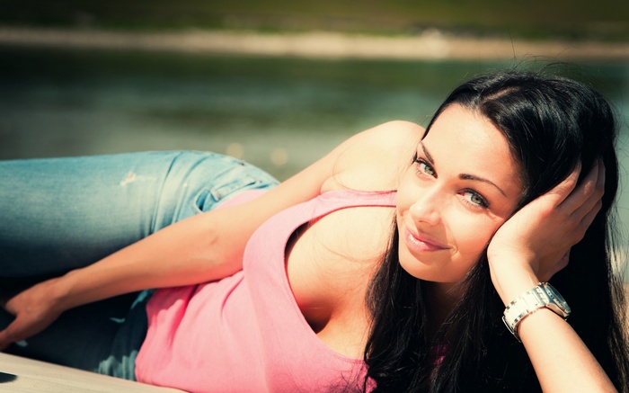 Woman in pink tank top and jeans lying down