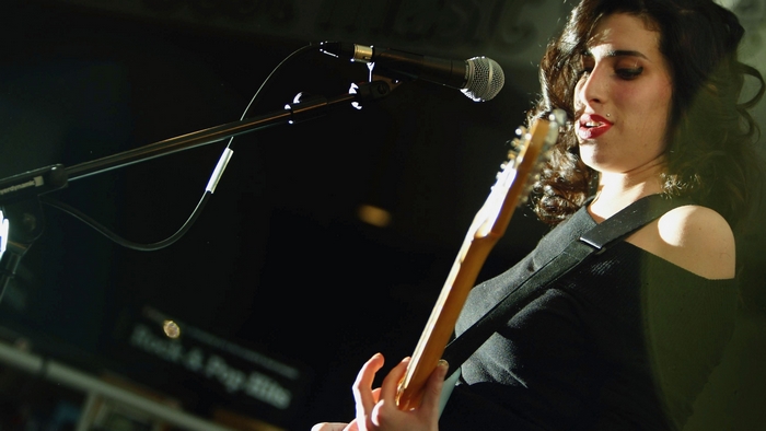 Amy Winehouse playing guitar on stage