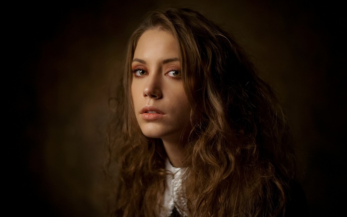 Woman with curly brown hair and white collar