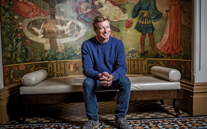 Simon Baker sitting on a bench in front of a mural