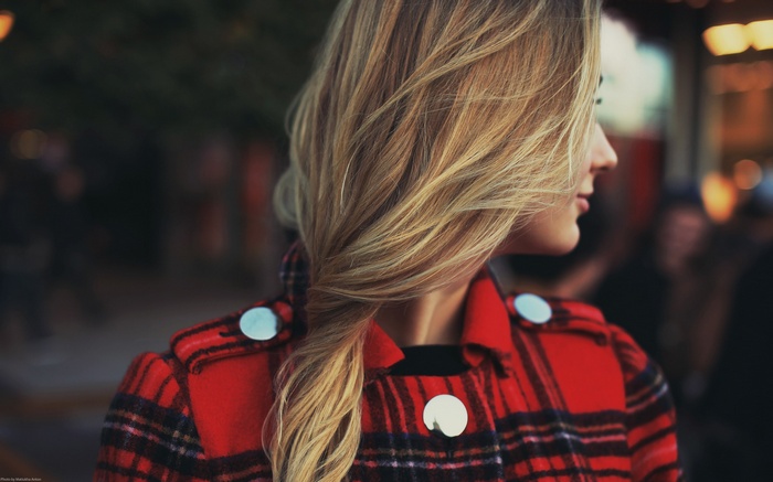 Woman with blonde braid wearing red plaid coat