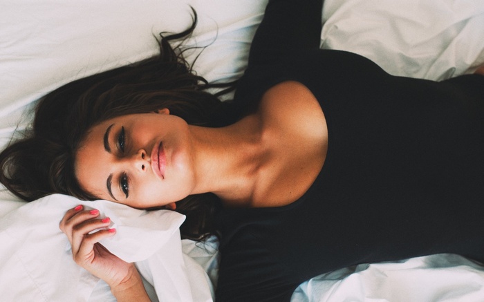 Woman lying on a white bed