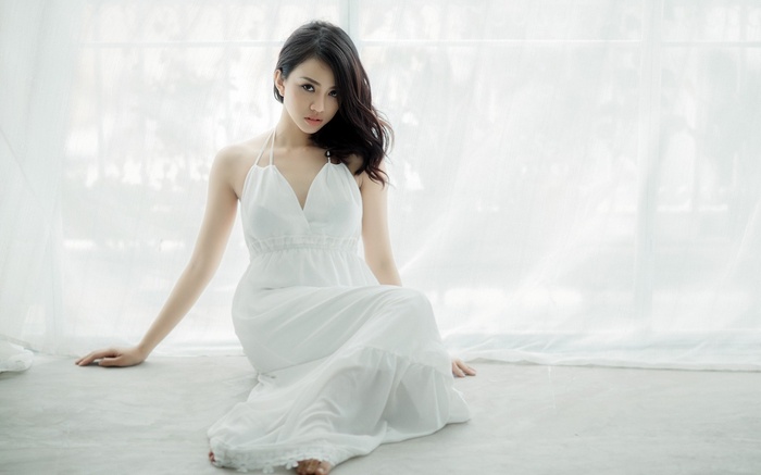 Woman in white dress sitting by window