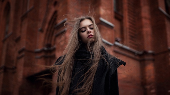 Woman with long hair in front of brick building