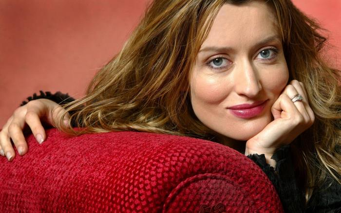 Natascha McElhone posing on a red couch