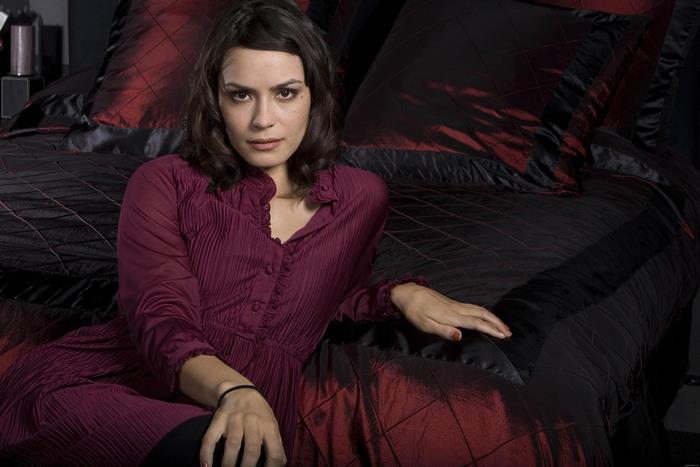 Shannyn Sossamon sitting on a bed