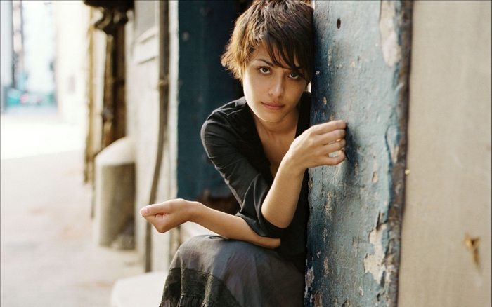 Shannyn Sossamon leaning against a weathered blue door