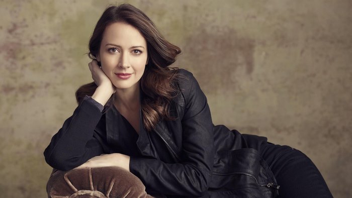 Amy Acker posing on a couch
