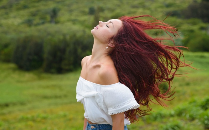 Woman with red hair in a white top outdoors