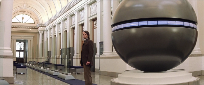 Guy Pearce in a Museum with a Large Sphere