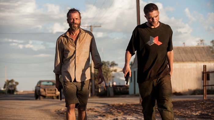 Guy Pearce and actor walking with guns