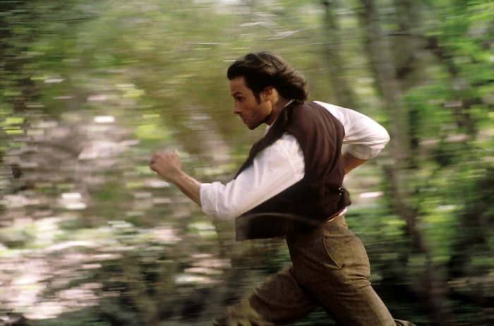 Guy Pearce running through a forest