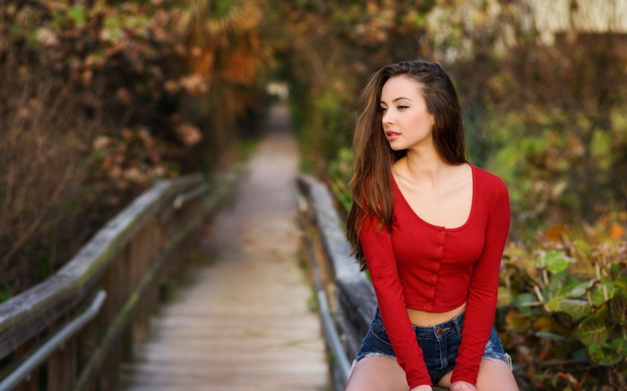 Woman in red top and denim shorts on a wooden walkway