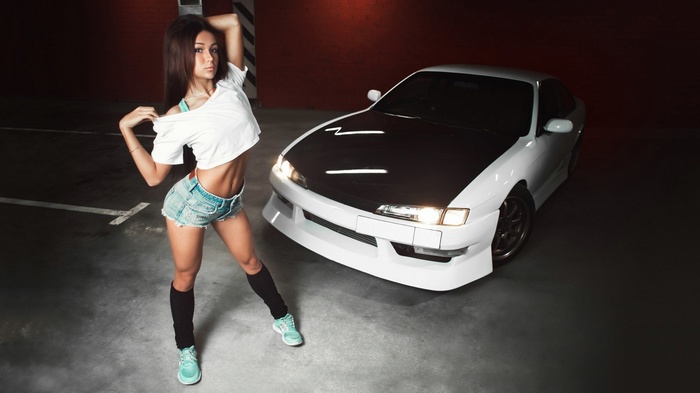 Woman posing next to a white sports car