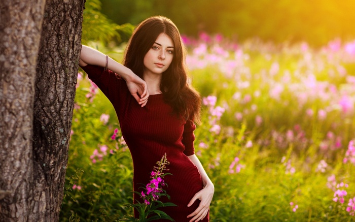 Young woman in a red dress in a field of flowers