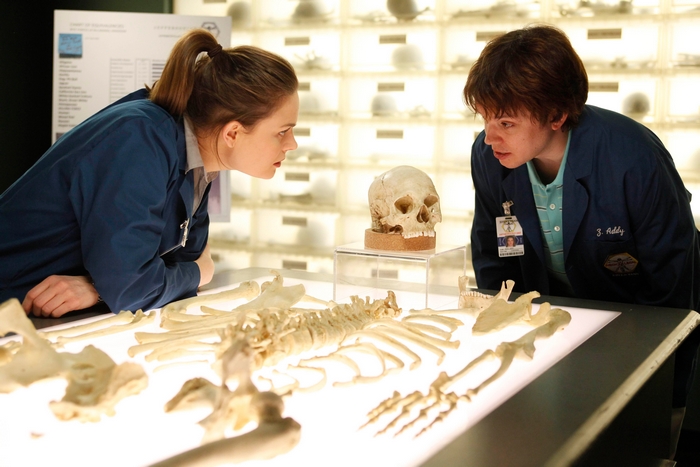 Two forensic anthropologists examine a skeleton and skull