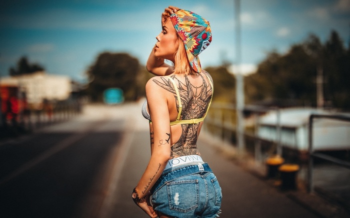 Woman with tattoos wearing denim shorts and a cap