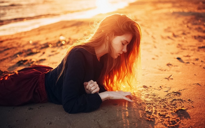 Girl drawing in sand at sunset