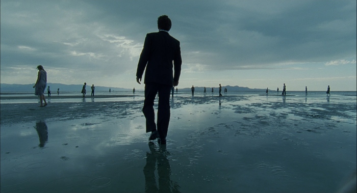 Sean Penn walking on a wet plain with other figures