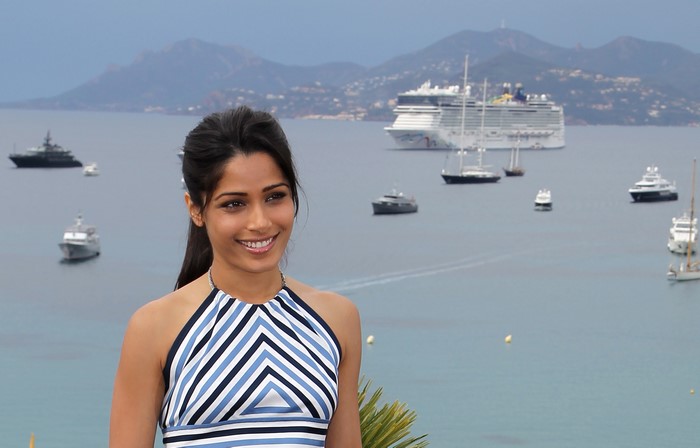 Freida Pinto on a boat with cruise ship in background
