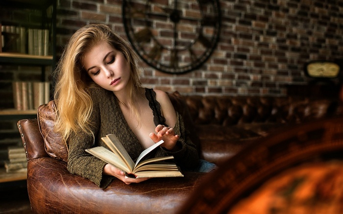 Woman reading a book on a leather couch