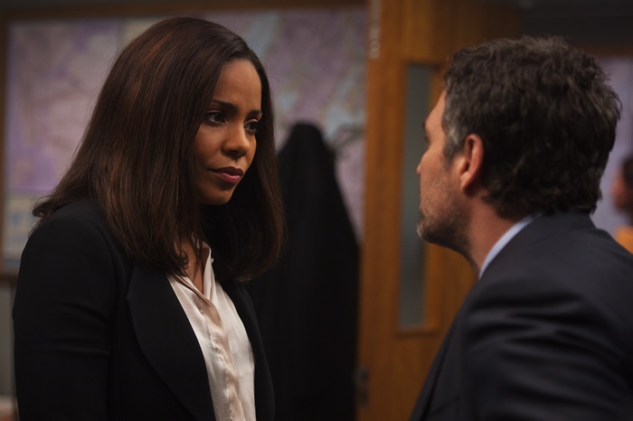 Woman in black suit talking to man in suit
