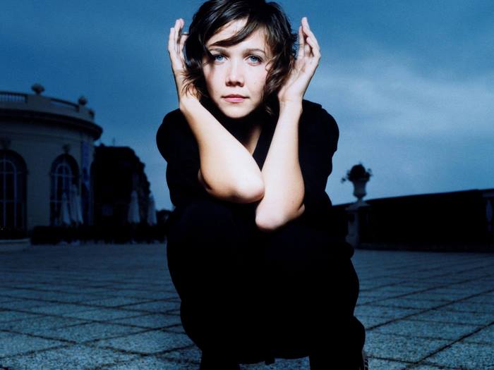 Maggie Gyllenhaal crouching outdoors