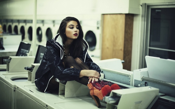 Woman sitting on washing machines in a laundromat