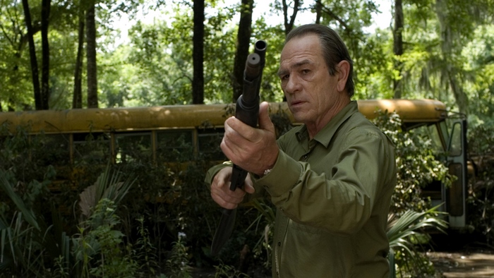 Tommy Lee Jones with shotgun in woods