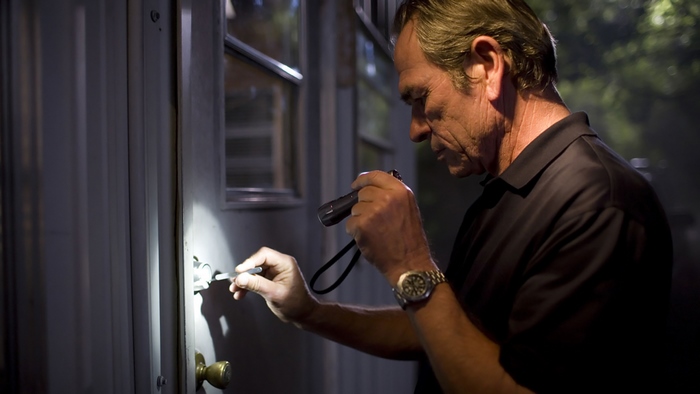 Tommy Lee Jones picking a lock with a flashlight