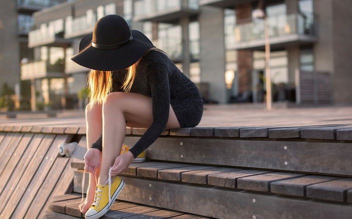 Woman in black hat tying yellow shoes