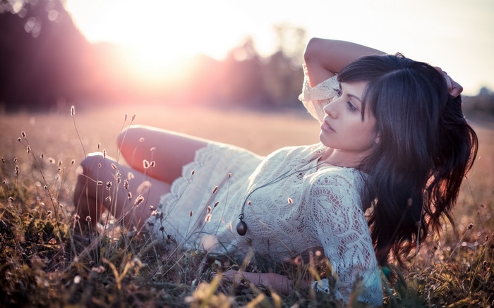 Woman lying in a field at sunset