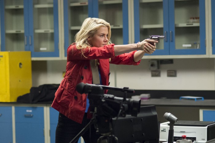 Rachael Taylor aiming a handgun in a lab